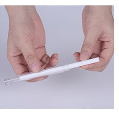 Pair of hands holding white cotton swab sticks against plain background.