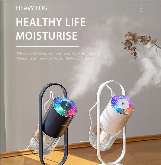 Dark blue USB air humidifier with colorful projection light releasing mist on wooden surface.