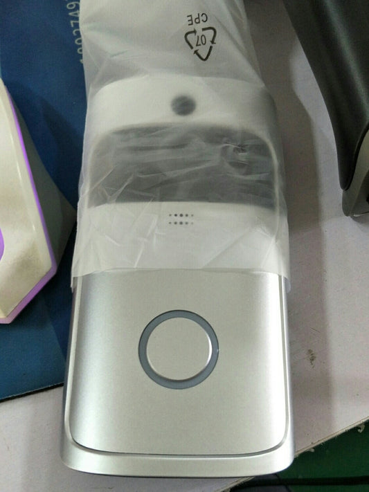 Silver smart doorbell with circular button and small camera lens above it wrapped in plastic packaging.