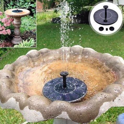 Solar-powered black floating fountain pump spraying water in stone birdbath outdoors.